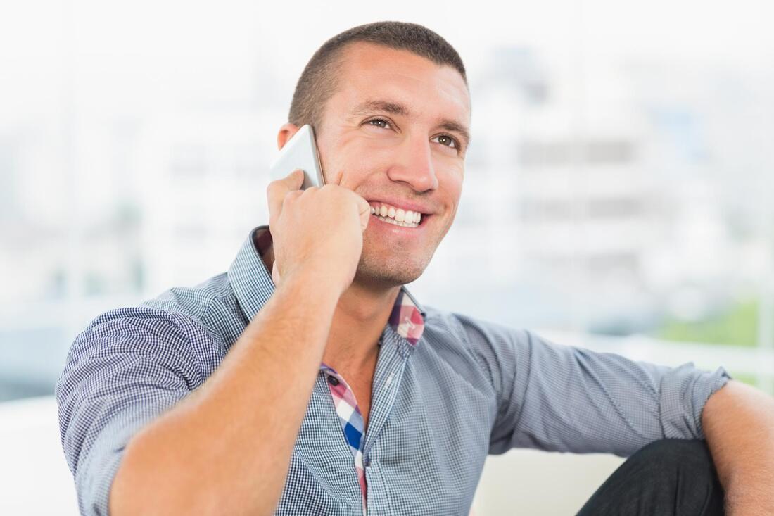 man smiling while talking on the phone